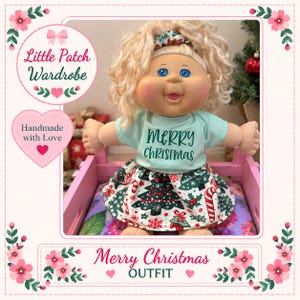 May include: A doll with blonde curly hair and blue eyes wearing a light green t-shirt with the text Merry Christmas in dark green letters and a skirt featuring a pattern of Christmas trees, candy canes, and snowflakes on a white background.