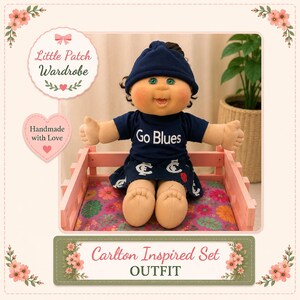 May include: A doll wearing a navy blue beanie, a navy blue t-shirt with the text Go Blues, and a matching navy blue skirt with white logos. The doll is seated in a pink wooden crate. Text on the image includes Little Patch Wardrobe and Carlton Inspired Set OUTFIT.