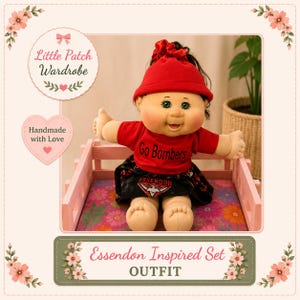 May include: A doll wearing a red beanie, a red t-shirt with the text Go Bombers, and a black skirt with the text ESSENDON and a red and black logo. The doll is seated in a light pink wooden crate with a floral patterned base.