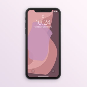 Könnte beinhalten: Ein schwarzes Smartphone zeigt einen Sperrbildschirm mit einem weichen, abstrakten Design in Rosa- und Brauntönen. Die Uhrzeit 10:24 und das Datum Dienstag, 13. September, sind sichtbar. Das Telefon befindet sich vor einem hellvioletten Hintergrund.