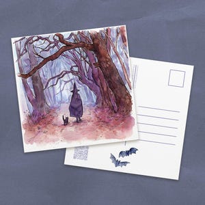 May include: Watercolor illustration of a witch walking through a misty forest with a black cat. The scene is depicted on a postcard, with a blank postcard and bat stickers nearby. The color palette includes shades of purple, brown, and gray.