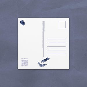 May include: White postcard with blue bat illustrations and the word "HALLOWEEN". The postcard has a QR code and lines for writing. The background is a textured, dark blue surface.