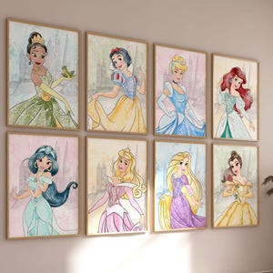 May include: Eight framed watercolour prints of Disney princesses in various gowns. The artwork features Tiana, Snow White, Cinderella, Ariel, Jasmine, Aurora, Rapunzel, and Belle. The prints are displayed on a light-coloured wall.