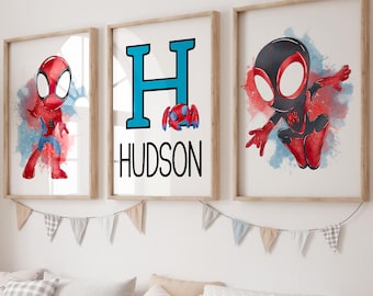 May include: Three framed superhero art prints. The prints feature a red and blue superhero, a large blue letter "H" with a small superhero, and a black and red superhero. The name "HUDSON" is below the letter. The prints are displayed above a storage bench.