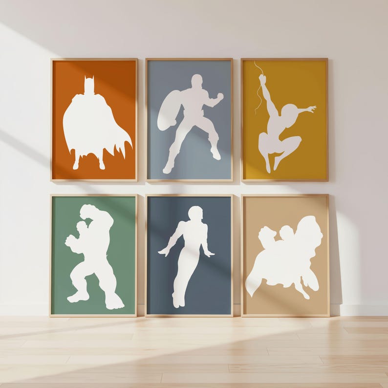 May include: Six framed art prints featuring white superhero silhouettes against colorful backgrounds. The prints are in wooden frames and include images of Batman, Captain America, Spider-Man, Hulk, and other figures. The backgrounds are in shades of orange, blue, yellow, green, and tan.