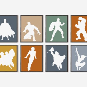 May include: Eight framed art prints featuring white superhero silhouettes against colorful backgrounds. The prints showcase iconic characters in action poses, including Batman, Captain America, and Spider-Man. The frames are black.