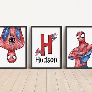 May include: Three framed art prints featuring Spider-Man. One shows Spider-Man upside down, another has a red "H" with Spider-Man figures and the name "Hudson", and the third depicts Spider-Man with arms crossed. The artwork is in red, blue, and black.