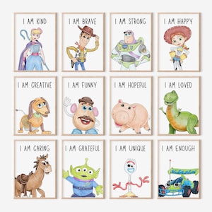 May include: A set of twelve framed watercolour prints featuring characters from a popular animated film series. Each print has a character illustration and a positive affirmation such as "I AM KIND" or "I AM BRAVE" in black text. The frames are light wood.