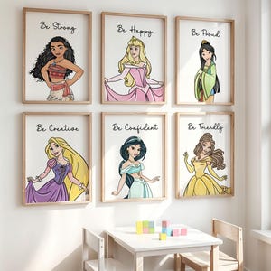Può includere: Sei stampe artistiche incorniciate con principesse Disney e frasi ispiratrici. Ogni stampa ha una cornice in legno e uno sfondo bianco. Le principesse sono raffigurate con abiti colorati. Le frasi includono "Be Strong", "Be Happy" e "Be Proud".
