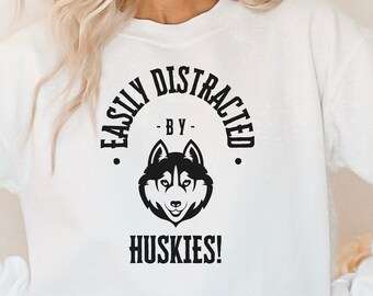 May include: White sweatshirt with a black graphic that says "Easily Distracted - By Huskies!" with a black husky silhouette.
