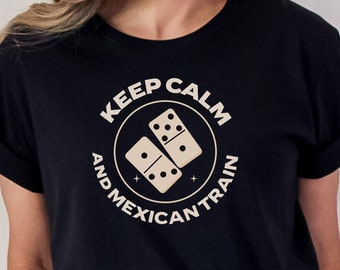 May include: Black t-shirt with the text "KEEP CALM AND MEXICAN TRAIN" in a circular design, featuring two dominoes. The shirt is a crew neck with rolled-up sleeves.