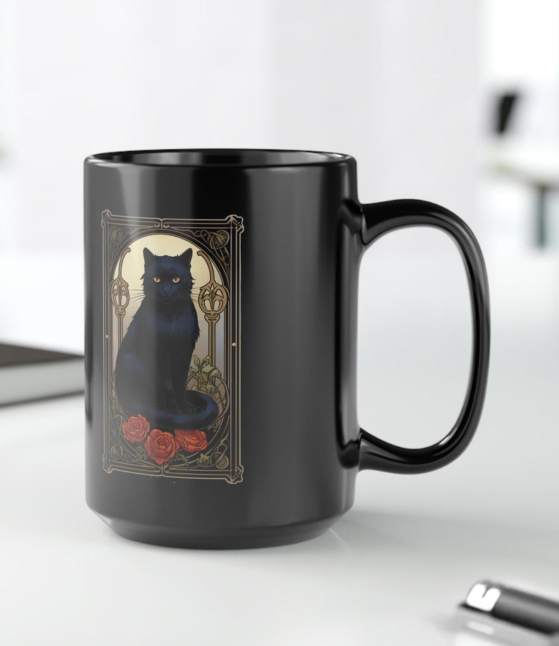 May include: Black ceramic coffee mug with a black cat illustration in an art nouveau style frame. The cat is sitting on a bed of red roses.