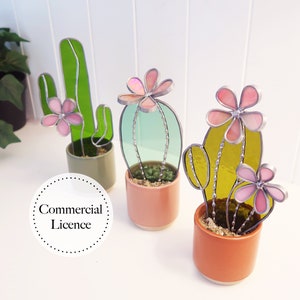 May include: Three stained glass cactus plants in terracotta pots. The cacti are green, blue, and yellow with pink flowers. The text "Commercial Licence" is visible in the image.