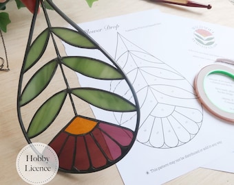 May include: A stained glass flower drop pattern featuring a red, orange, and green flower design. The pattern is printed on white paper with the title "Flower Drop" and a note that the pattern may not be distributed or sold.