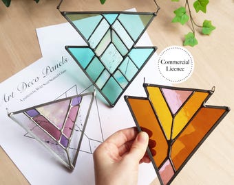 May include: Three Art Deco stained glass panels in triangular shapes. One is teal and white, another is purple and pink, and the third is orange and pink. Each panel has a metal frame and a chain for hanging.