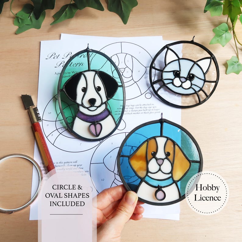 May include: Three stained glass pet portraits: a dog in an oval frame, a cat in a round frame, and a dog in a round frame. The dog portraits have black and white, and brown and white coloring. The cat portrait is light blue and white. The text "CIRCLE & OVAL SHAPES INCLUDED" is visible.