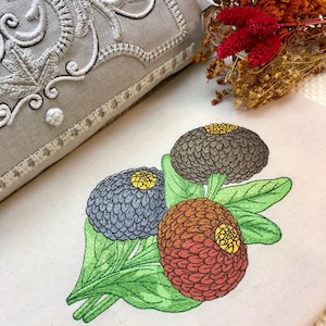 May include: Embroidered design of three colorful flowers with green leaves on a white fabric background.