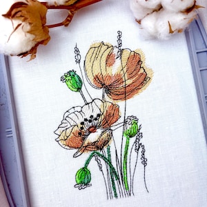 May include: Embroidered floral design featuring orange and white poppies with green stems and buds. The artwork is on white fabric, held in a gray embroidery hoop. Cotton branches with fluffy white blooms are in the background.