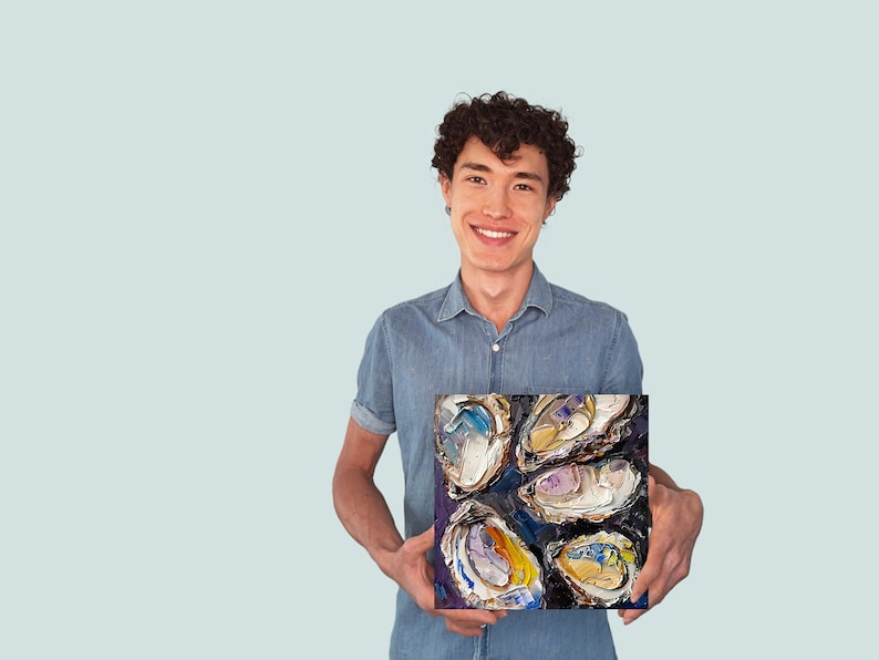 May include: A man is holding a painting of a group of oysters. The oysters are painted in a variety of colors, including purple, blue, yellow, and white. The painting is on a dark background.