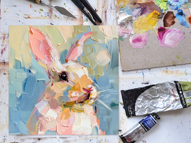 May include: A close-up painting of a white rabbit with pink ears and a blue background. The painting is done in a loose, impressionistic style with visible brushstrokes.
