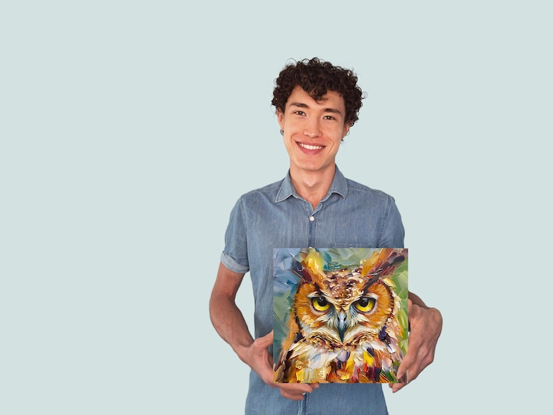 May include: A man is holding a painting of an owl with a colorful background. The owl has yellow eyes and brown feathers. The painting is framed and has a white border.