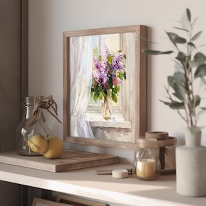 May include: A framed painting of a bouquet of purple lilacs in a vase on a windowsill. The window is open and there is a white curtain blowing in the breeze. The painting is done in a realistic style with soft colors.