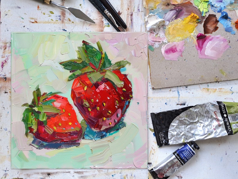 May include: A close-up of a painting of two red strawberries with green leaves on a light green background.