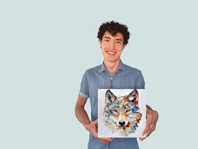 May include: Square canvas art featuring a colorful, textured painting of a wolf's face. The artwork uses a palette of blues, oranges, and whites. The painting is held by a person wearing a blue denim shirt.