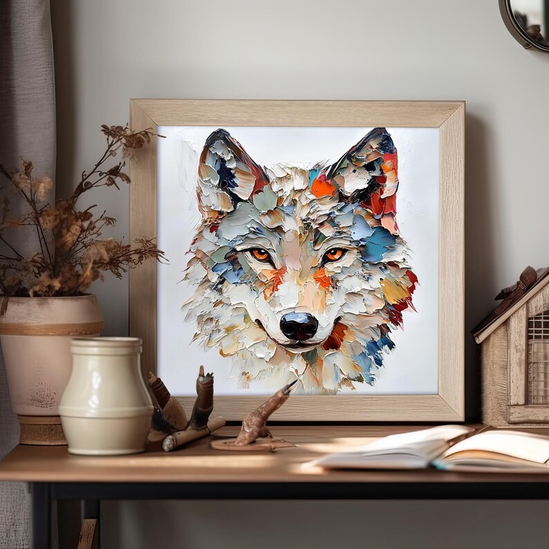 May include: A framed artwork featuring a textured, colorful painting of a wolf's face. The wolf's fur is depicted with thick brushstrokes in shades of white, blue, orange, and yellow. The eyes are a warm orange, and the frame is light wood.