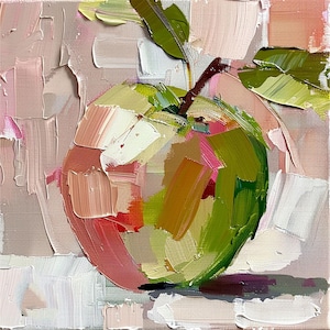 May include: A close-up of a painting of a red apple with green leaves on a pink and white background.