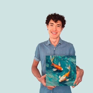 May include: Square canvas art featuring two koi fish swimming in a turquoise pond. The fish are orange and white, with detailed brushstrokes creating a textured, artistic effect. The artwork is held by a person.