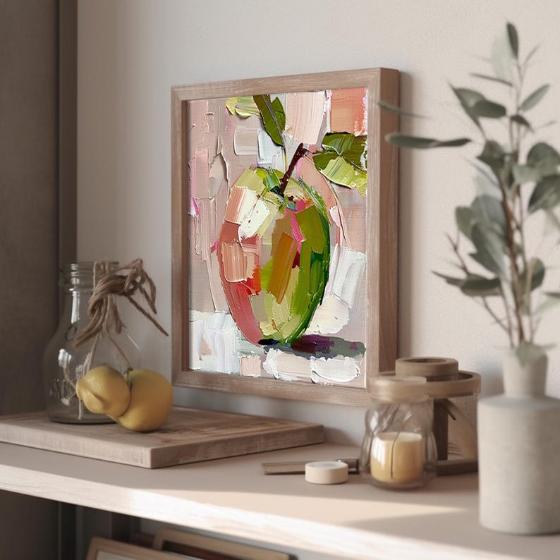 May include: A painting of a green apple with a pink blush, with a wooden frame. The apple is painted in a loose, impressionistic style with visible brushstrokes.