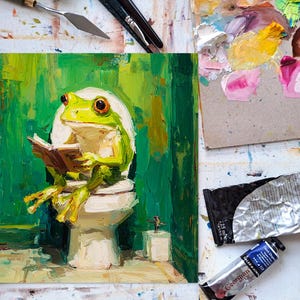 以下が含まれることがあります： トイレで本を読む緑色のカエルの油絵。このアートワークは、緑、黄、茶色のパレットを使用しています。絵の具チューブとパレットナイフが見え、アーティストのスタジオ環境を示唆しています。