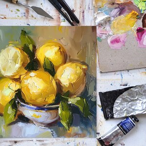 May include: A still life painting of lemons in a white bowl with green leaves. The lemons are yellow and have a textured surface. The bowl is white with blue and green accents. The background is a light blue and green.