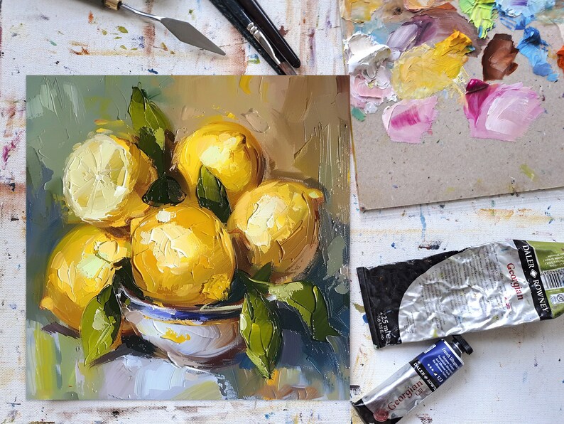 May include: A still life painting of lemons in a white bowl with green leaves. The lemons are yellow and have a textured surface. The bowl is white with blue and green accents. The background is a light blue and green.