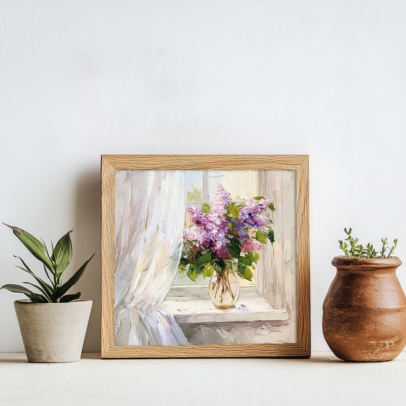 May include: A framed painting of a bouquet of purple lilacs in a glass vase, sitting on a windowsill with a white curtain. The painting is in a light wood frame.