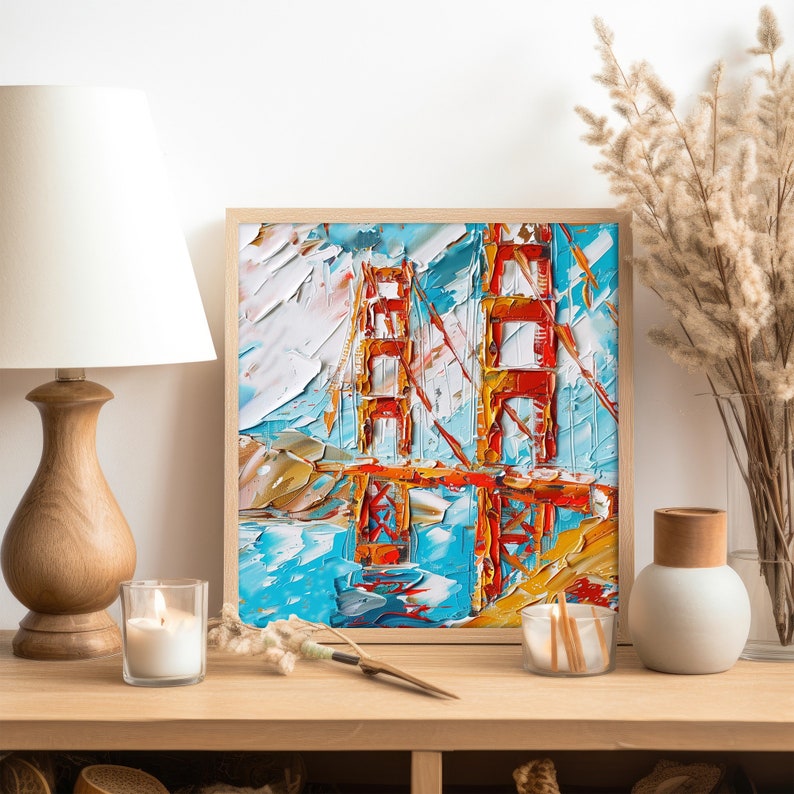 May include: A framed painting depicting the Golden Gate Bridge in San Francisco. The artwork is created using a thick, impasto style with vivid colours and bold brushstrokes. The bridge is painted in shades of red, orange, and yellow, while the water is a vibrant blue. The sky is a mix of white and blue.