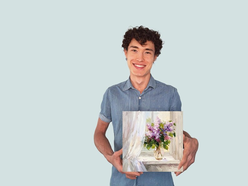 May include: A man in a blue shirt is holding a painting of a vase of purple flowers in front of a window with white curtains.