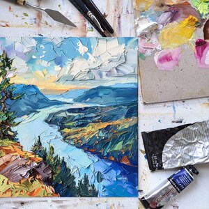 May include: A painting of a river winding through a valley with a mountain in the background. The sky is blue with white clouds. The painting is done in a thick, impasto style.