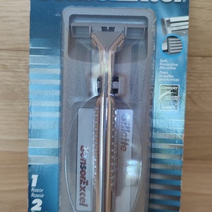 May include: A silver and gold Gillette SensorExcel razor with two cartridges. The packaging features the brand name and product name in blue text. The razor has a comfort blade and protective microfins.