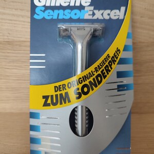 May include: A silver Gillette Sensor Excel razor with a blue and yellow package. The package says "Der Original-Rasierer Zum Sonderpreis".