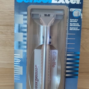 May include: A silver Gillette Sensor Excel razor with a two-blade cartridge. The packaging is blue and white with the text "Protective Microfins" and "Skyddande Mikrolameller" in English and Swedish.