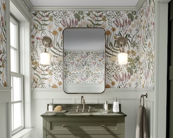 Puede incluir: Un tocador de baño verde con una encimera blanca y un espejo encima. El tocador tiene tres cajones y un estante debajo. Las paredes están cubiertas con papel tapiz floral. El tocador está en un baño con zócalo blanco y suelo de madera oscura.