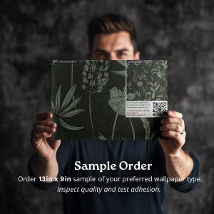 May include: A person is holding a 13 inch by 9 inch sample of wallpaper with a botanical print. The text on the sample reads "100% scale print preview" and "pattern preview". The text below the sample reads "Sample Order" and "Order 13in x 9in sample of your preferred wallpaper type. Inspect quality and test adhesion."