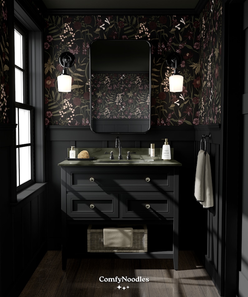 May include: A black bathroom vanity with a dark green countertop and a white porcelain sink. The vanity has three drawers and a lower shelf. The walls are covered in dark floral wallpaper with a black mirror above the sink. Two black sconces with white glass shades are mounted on the wall.