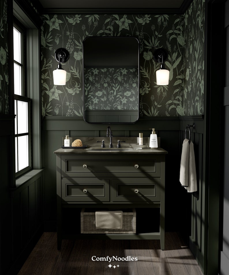 May include: A dark green bathroom vanity with a white porcelain sink and a mirror above it. The vanity has three drawers and a lower shelf with a wicker basket. The walls are covered in a green floral wallpaper. The vanity is lit by two black wall sconces with white glass shades.