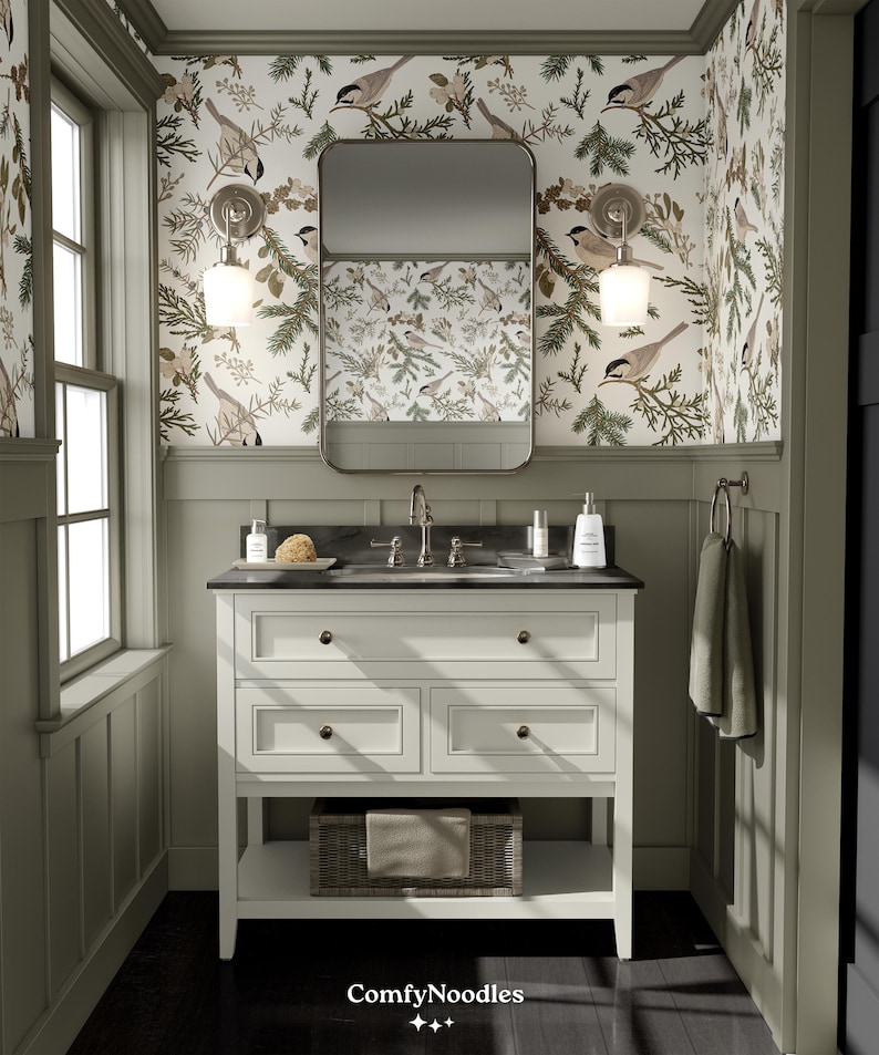 May include: A white bathroom vanity with three drawers and a lower shelf. The vanity has a black countertop with a white porcelain sink and chrome faucets. The vanity is in front of a wall with green wallpaper featuring a repeating pattern of birds and pine branches. The wallpaper has the text "ComfyNoodles" printed on it.