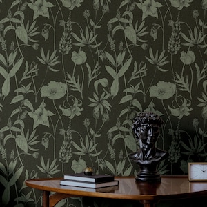 May include: A dark green wallpaper featuring a botanical pattern of leaves and flowers. A black bust of a man and two books are on a wooden table in front of the wallpaper.