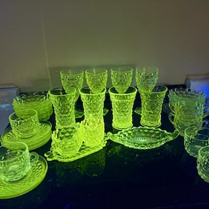 Könnte beinhalten: Eine Sammlung von Vintage-Uran-Glas-Teetassen, Untertassen und einer kleinen Servierplatte. Das Glas ist in einem leuchtenden Gelbgrün gehalten und hat eine strukturierte, genoppte Oberfläche.
