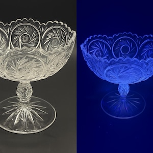 May include: Clear glass pedestal bowl with intricate starburst and swirl patterns. The bowl has a scalloped rim and a round base. The image shows the bowl in normal light and under a black light, revealing a blue glow.